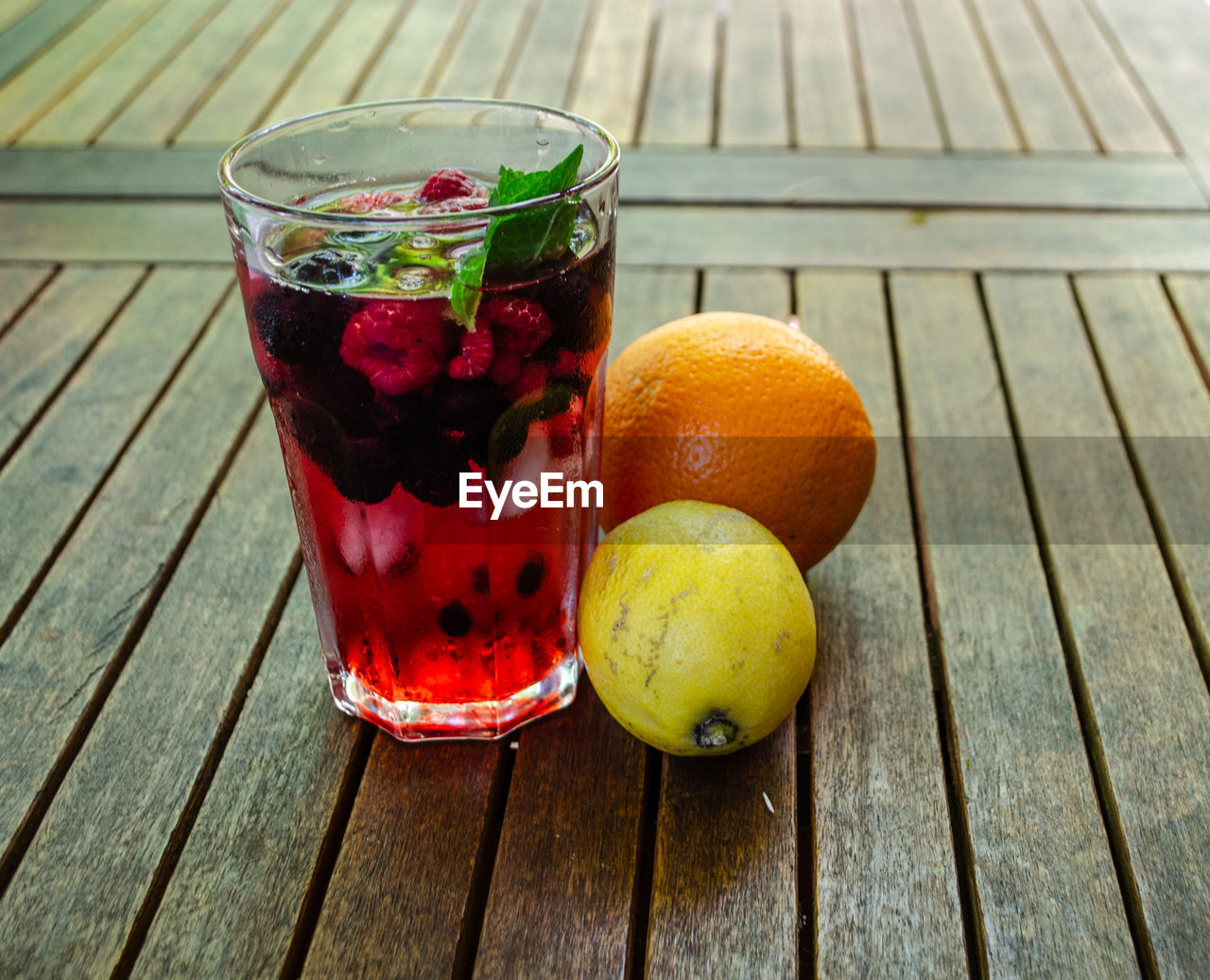 Directly above shot of glass with raspberry on wooden table