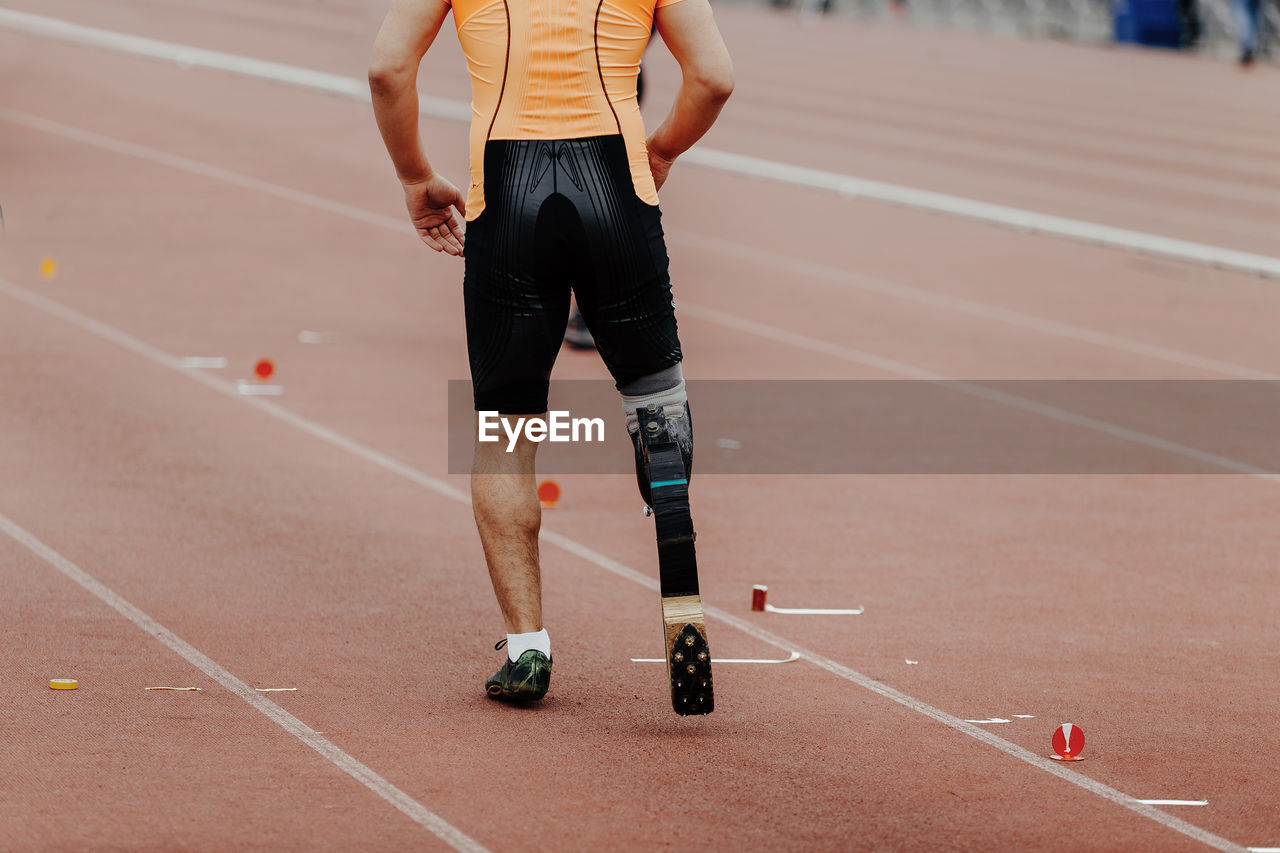 Low section of man with amputated leg running on track