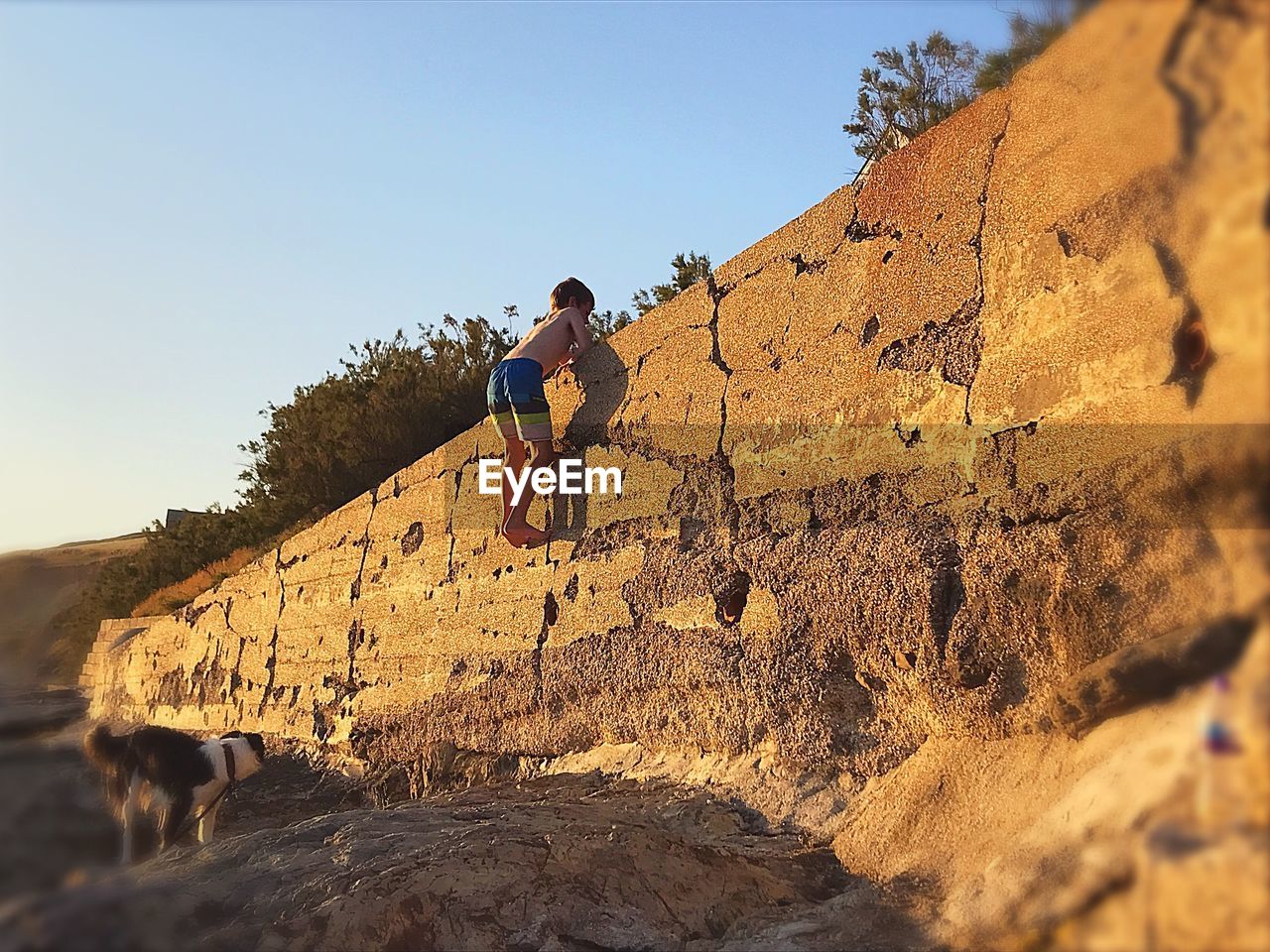 LOW ANGLE VIEW OF MAN JUMPING ON MOUNTAIN AGAINST SKY