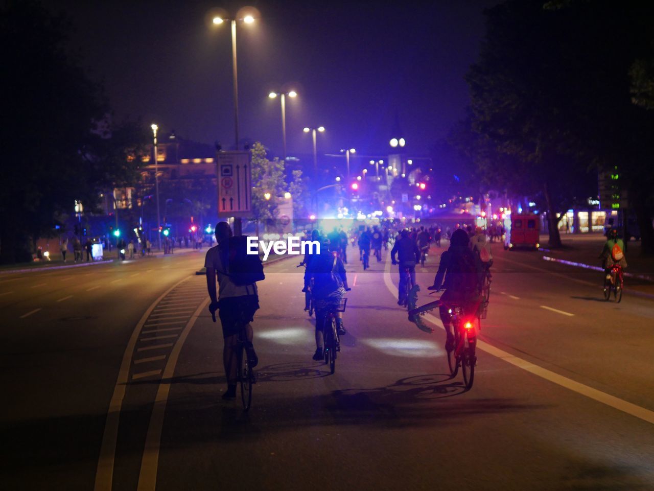 PEOPLE ON ILLUMINATED ROAD AT NIGHT