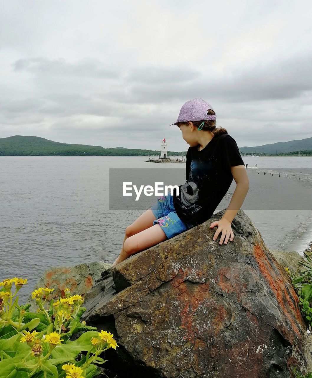 MAN STANDING ON ROCK AGAINST SEA