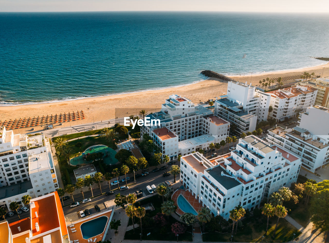 Aerial view of beach, boardwalk and buildings in quarteira, algarve, portugal on a sunny summer day