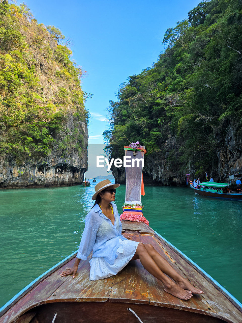 rear view of woman sitting on boat in sea against mountain