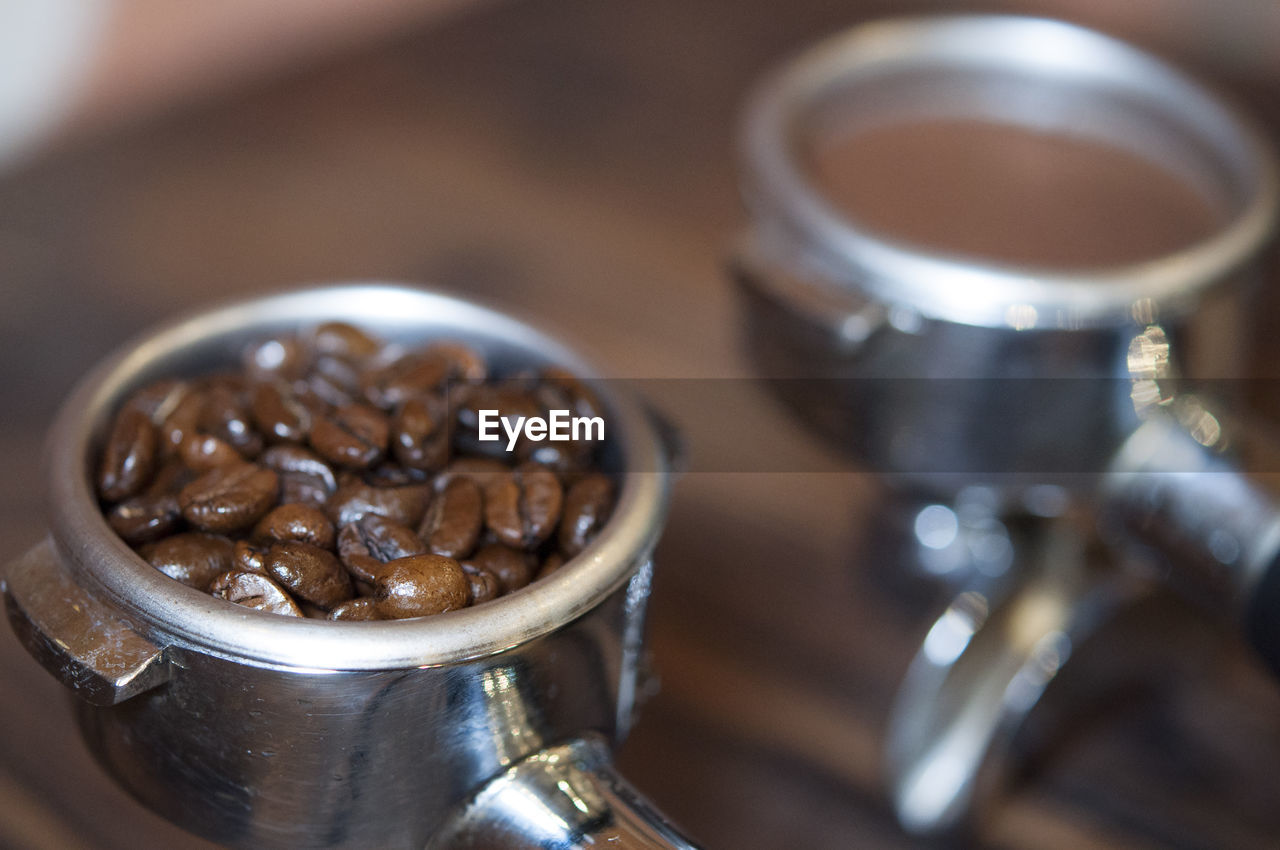 Close-up of ground coffee and roasted coffee beans in filters on table