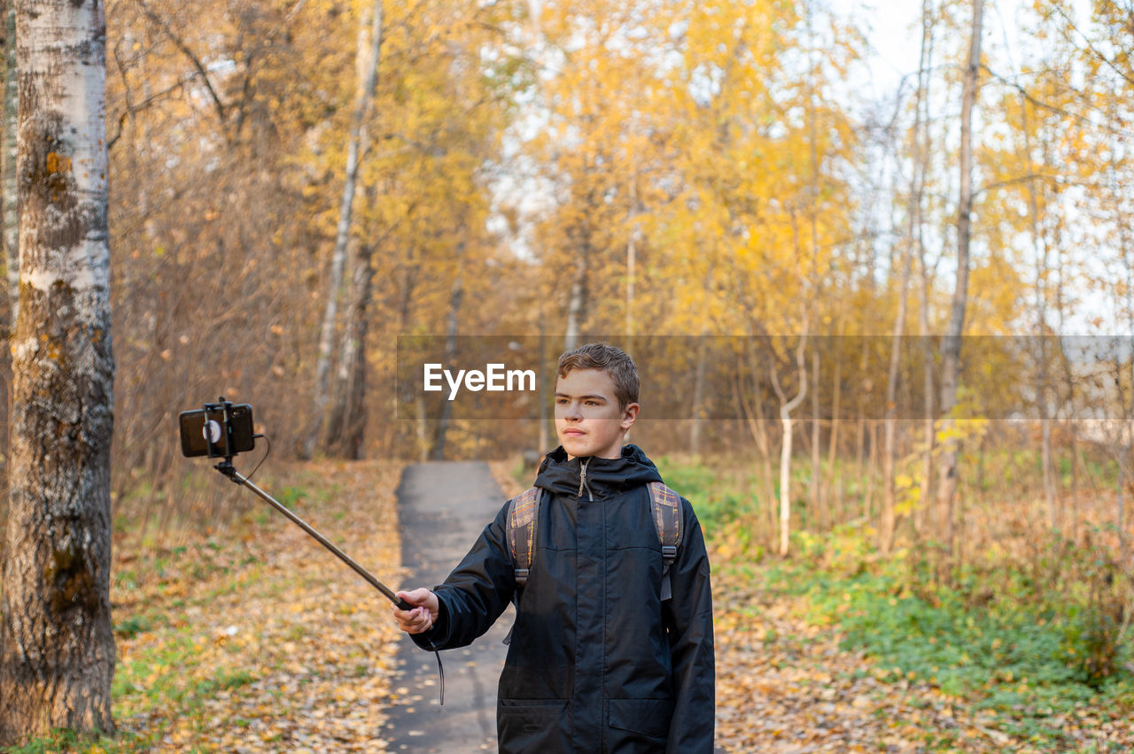 Boy vlogging in forest during autumn