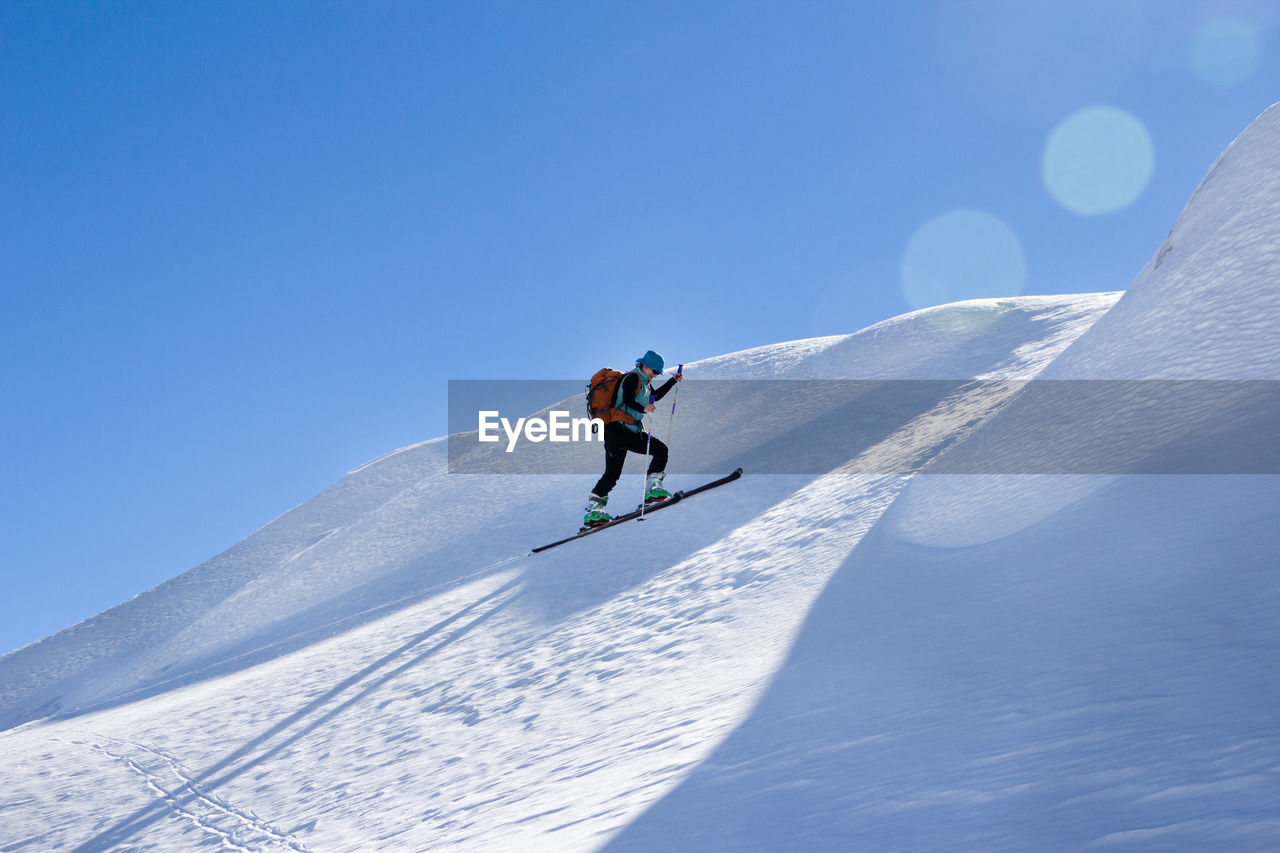 Man skiing on snowcapped mountain against sky