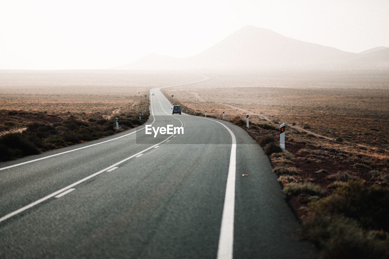 EMPTY ROAD ALONG LANDSCAPE WITH MOUNTAIN IN BACKGROUND