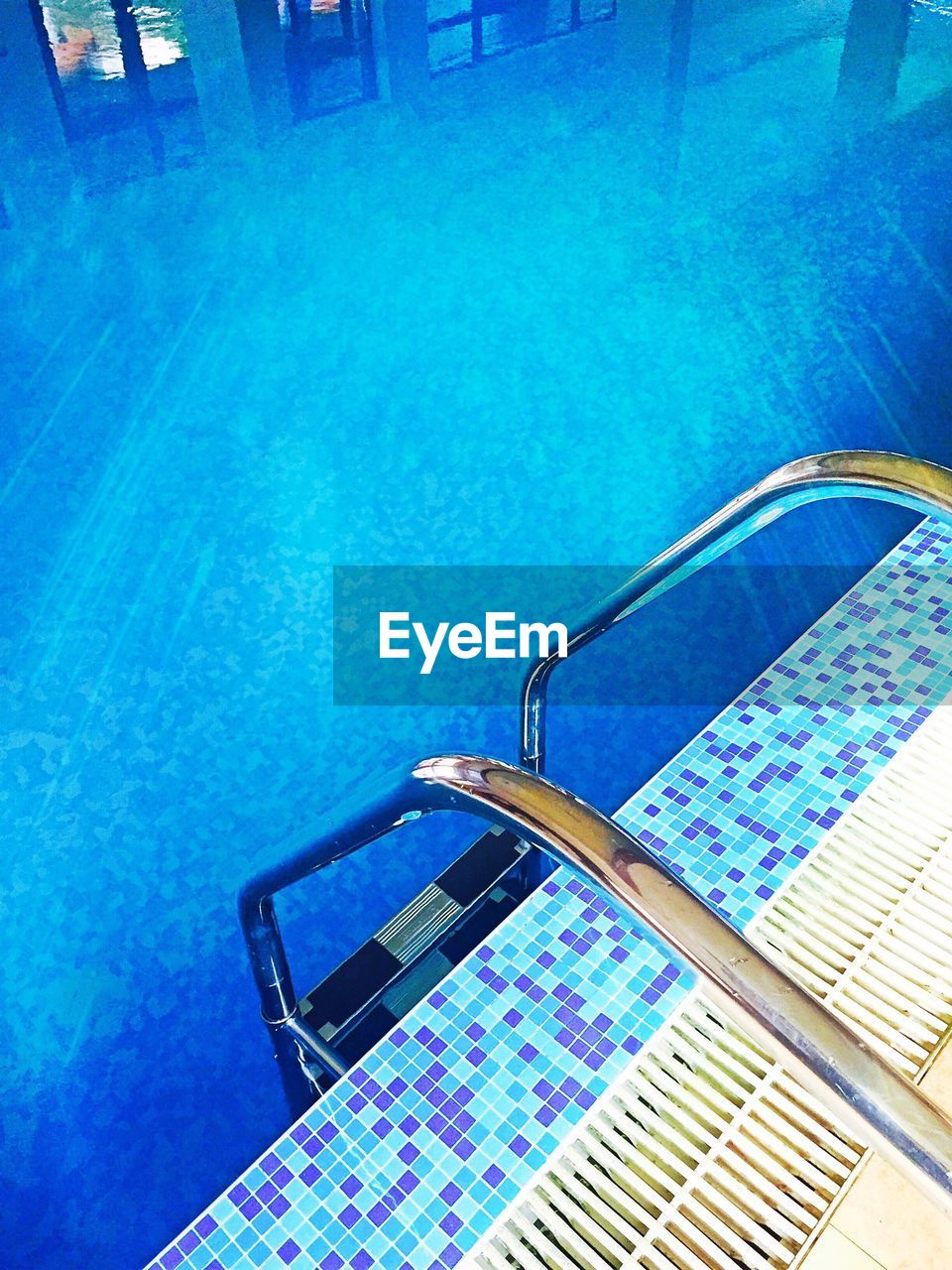 HIGH ANGLE VIEW OF SWIMMING POOL AGAINST BLUE SEA