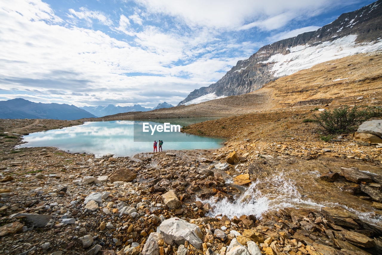 Two backpackers hiking along iceland trail near alpine lake in yoho