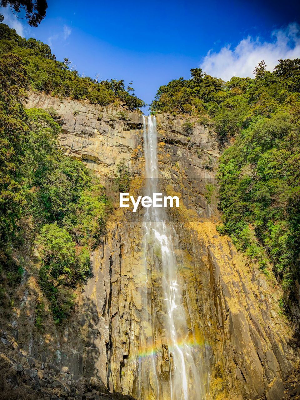 LOW ANGLE VIEW OF WATERFALL ON MOUNTAIN AGAINST SKY