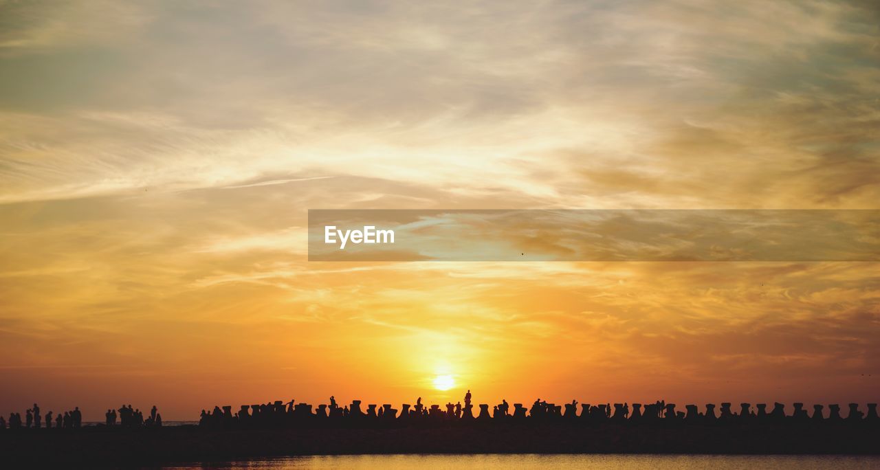 Silhouette of built structure on sea against sky during sunset