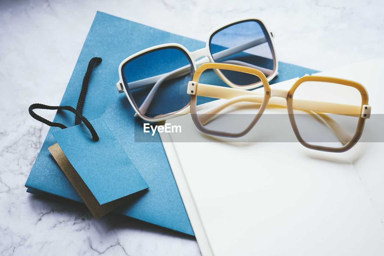 glasses, eyeglasses, vision care, indoors, no people, studio shot, still life, blue, fashion accessory, eyewear, paper, high angle view, copy space, font, group of objects, wedding ring