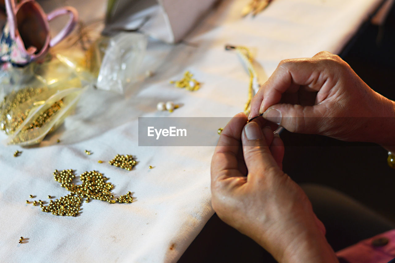 Cropped hands of man making jewelry on table