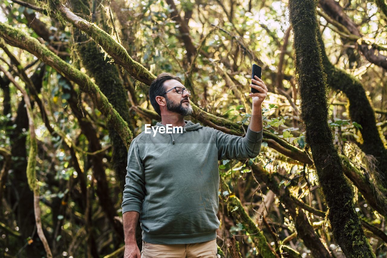 Young man using mobile phone in forest