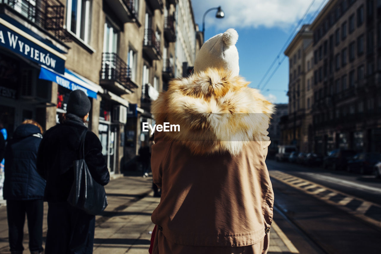 REAR VIEW OF WOMEN WALKING ON STREET IN CITY