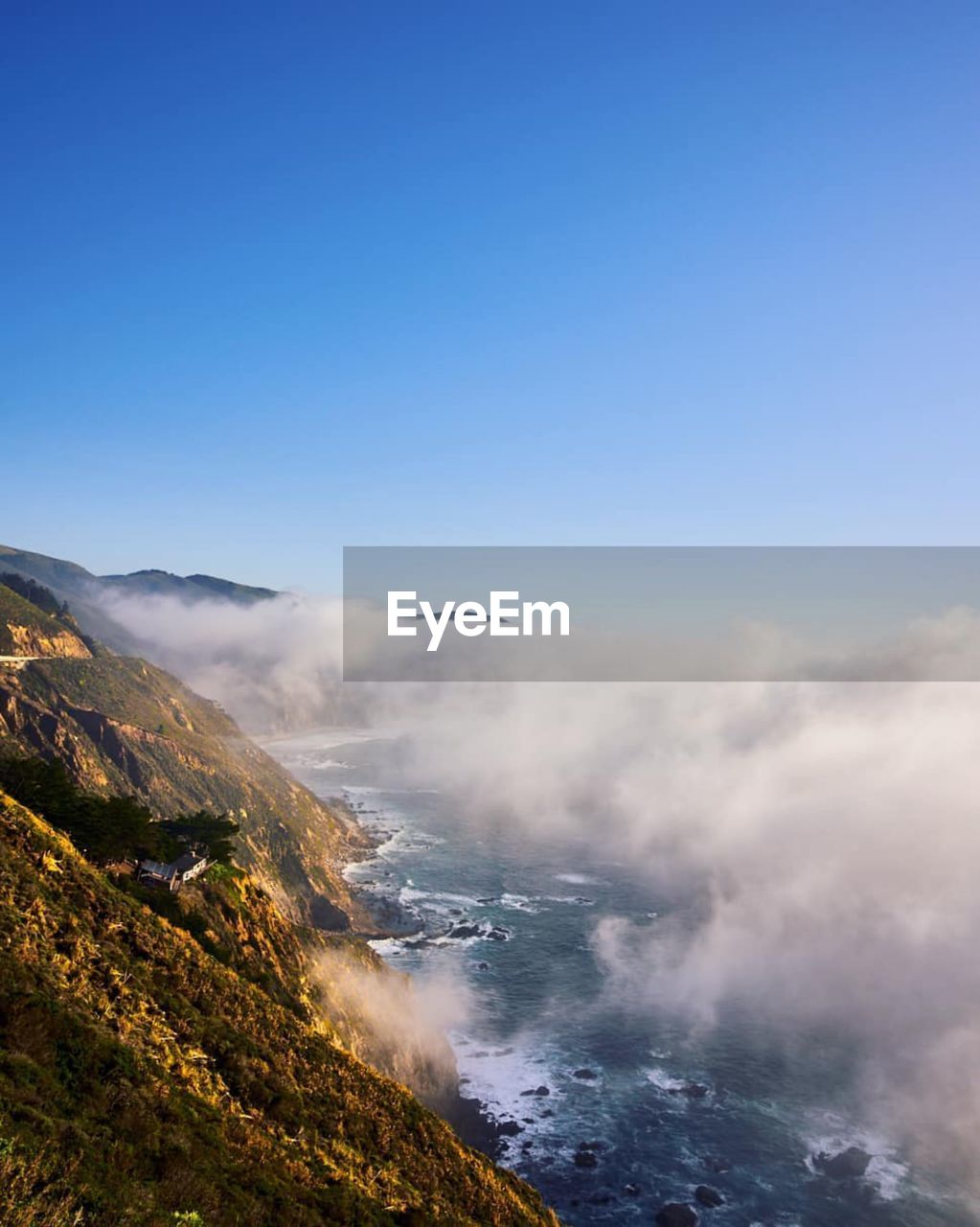 Scenic view of sea and mountains against clear blue sky