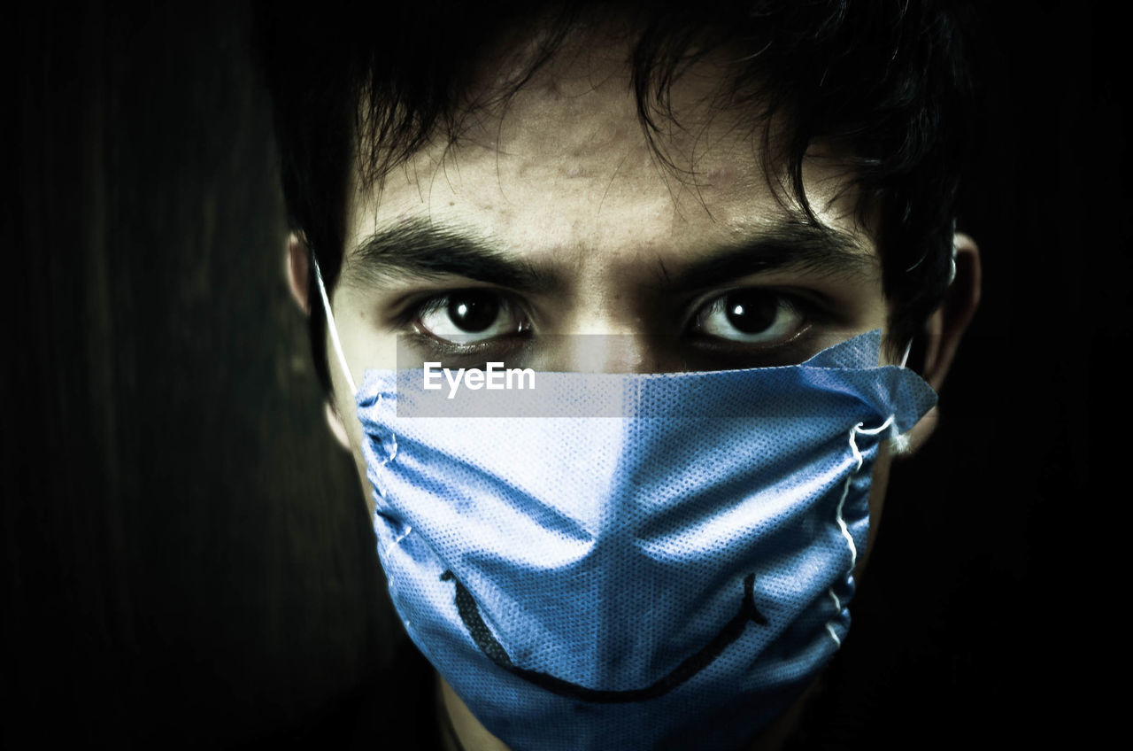 Close-up portrait of man wearing pollution mask with smiling sign