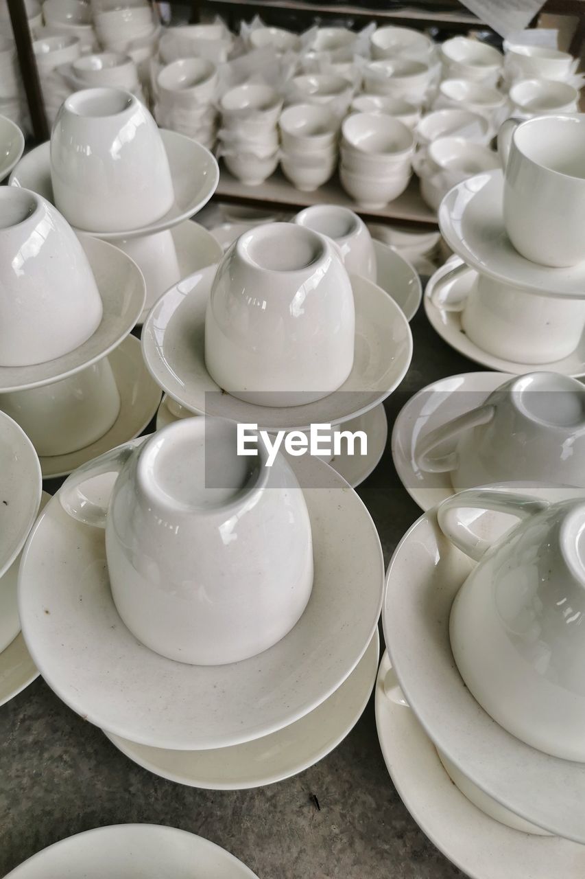 HIGH ANGLE VIEW OF EMPTY TEA CUPS ON TABLE WITH KITCHEN