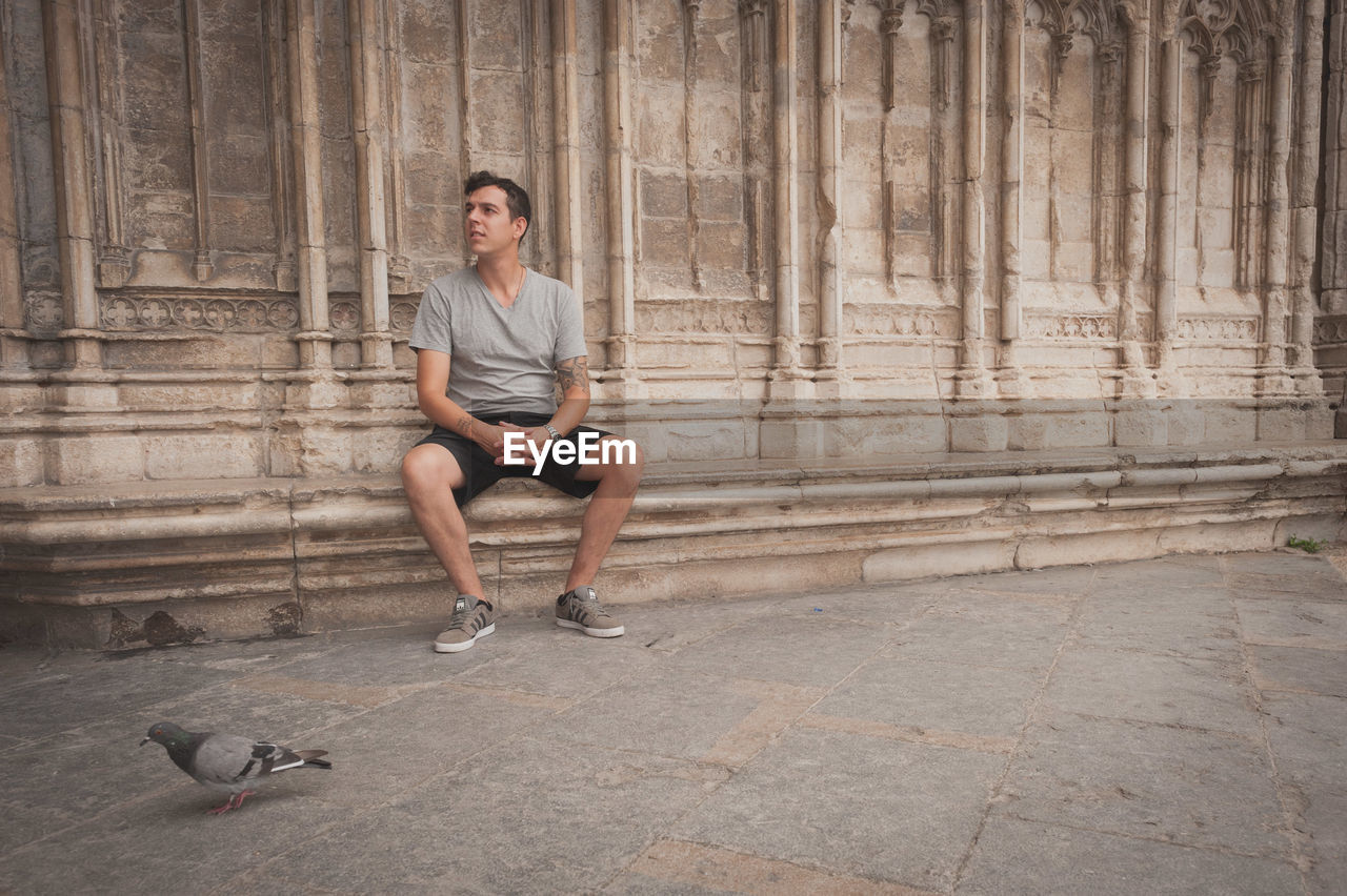 Man sitting near pigeon