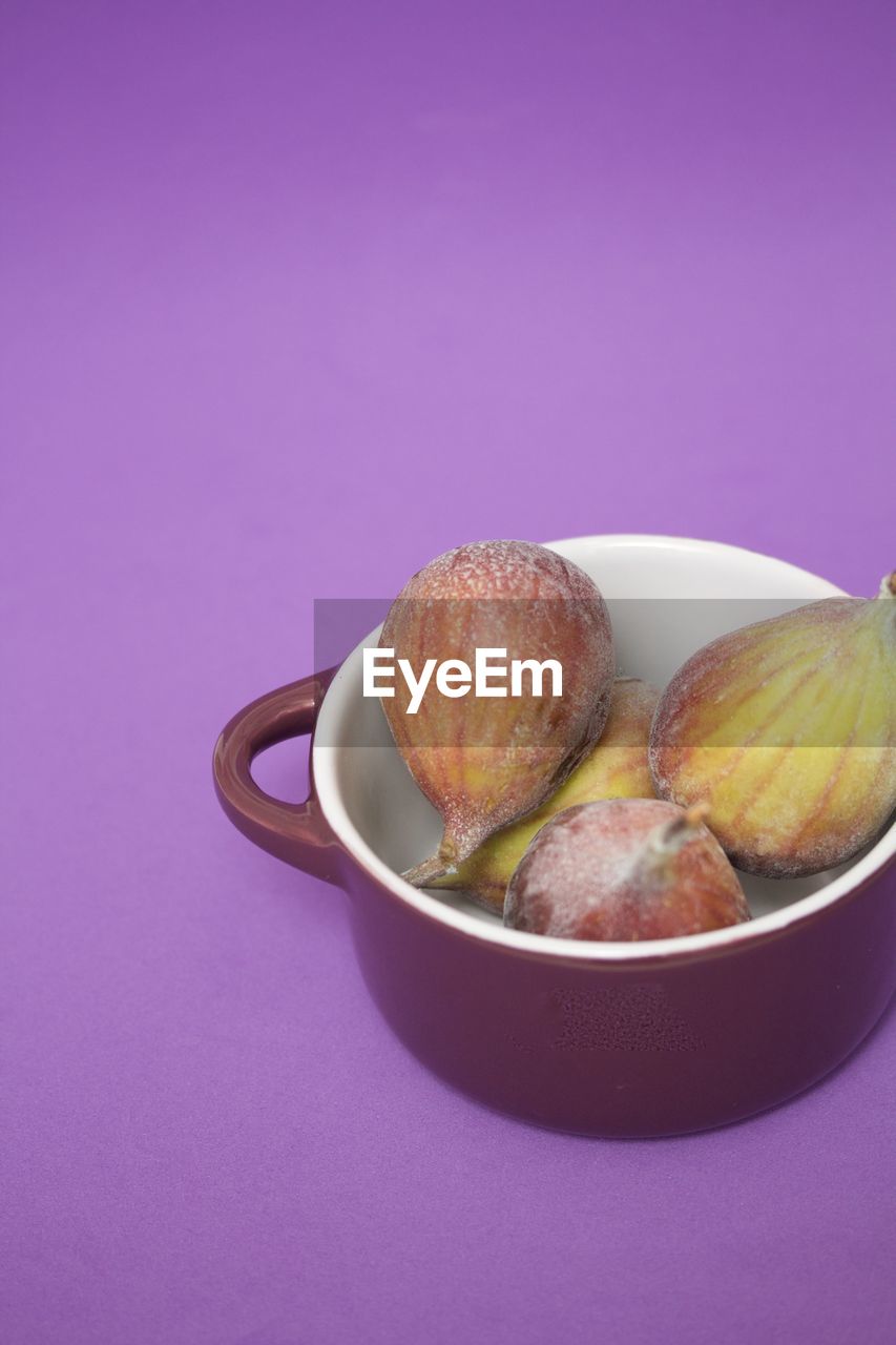 Figs in a purple bowl on purple background