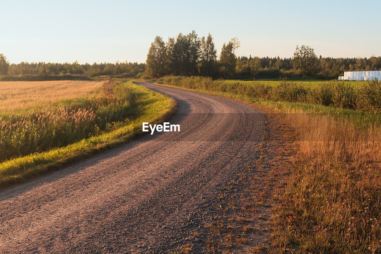 VIEW OF ROAD AMIDST FIELD AGAINST SKY