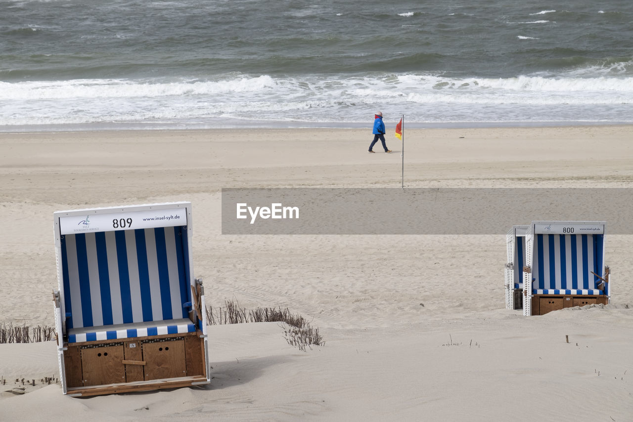 REAR VIEW OF MAN AND WOMAN ON BEACH