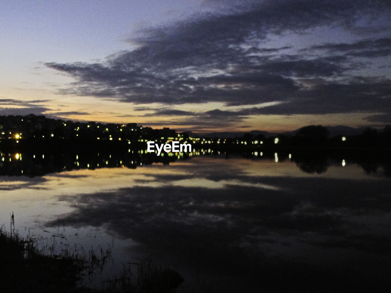 SCENIC VIEW OF LAKE AGAINST CLOUDY SKY DURING SUNSET