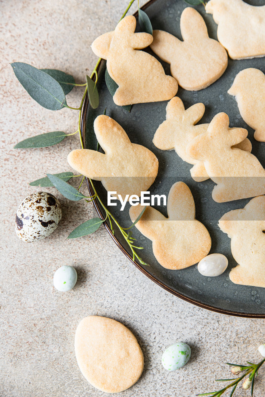 Easter cookies with candies shaped eggs on a ceramic plate and floral decor and quail eggs