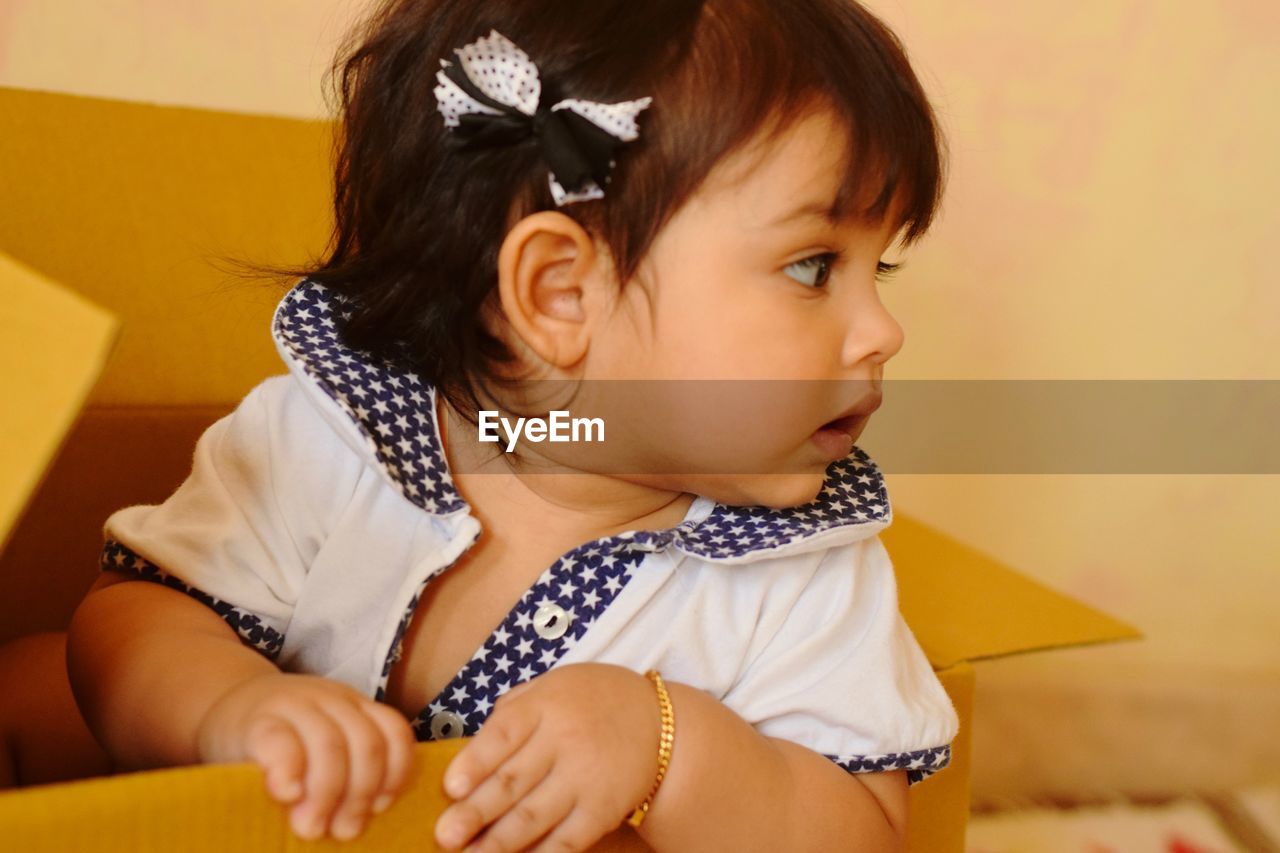 Close-up of cute toddler girl relaxing in cardboard box at home