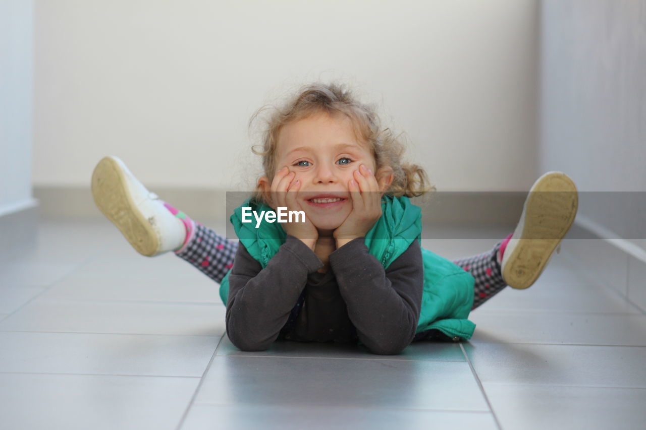 Portrait of cute girl lying on tiled floor