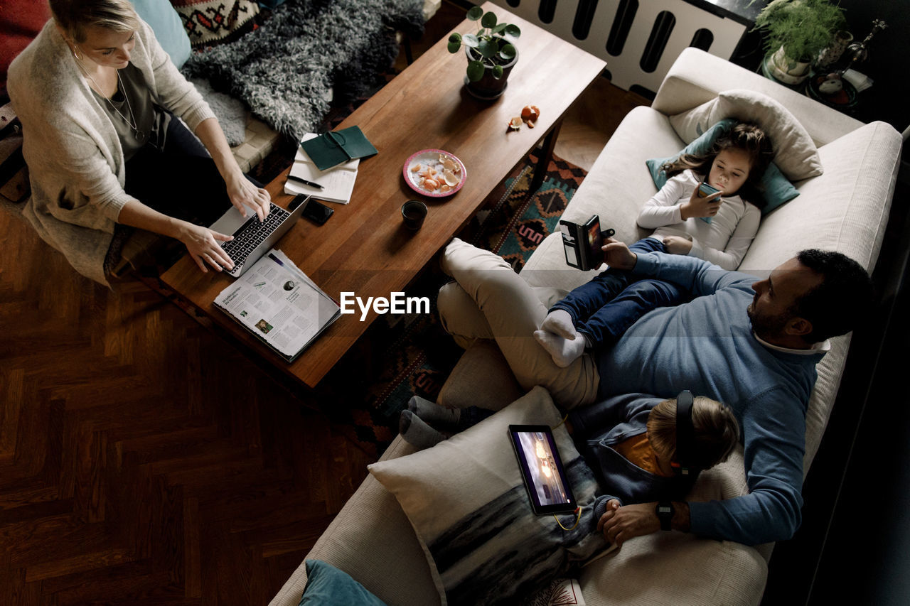 High angle view of family using various technologies in living room at home