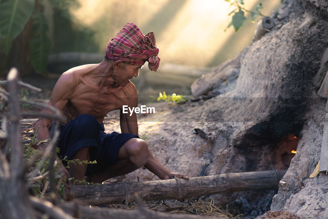 Senior man burning bamboo in forest