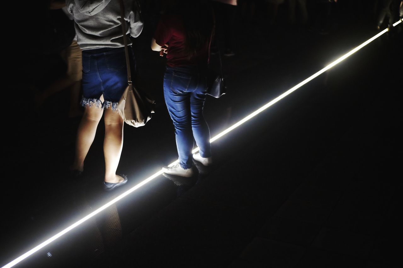 Low section of women standing on illuminated floor