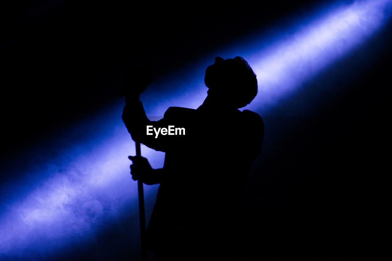 SILHOUETTE OF MAN WITH GUITAR IN BACKGROUND