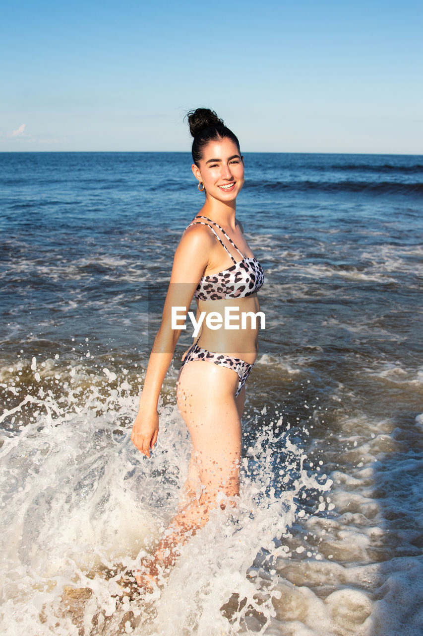 Portrait of woman in bikini standing at beach