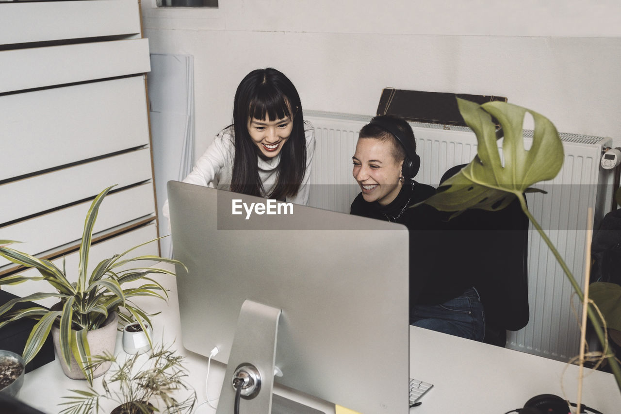 Smiling entrepreneurs working on computer at place of work