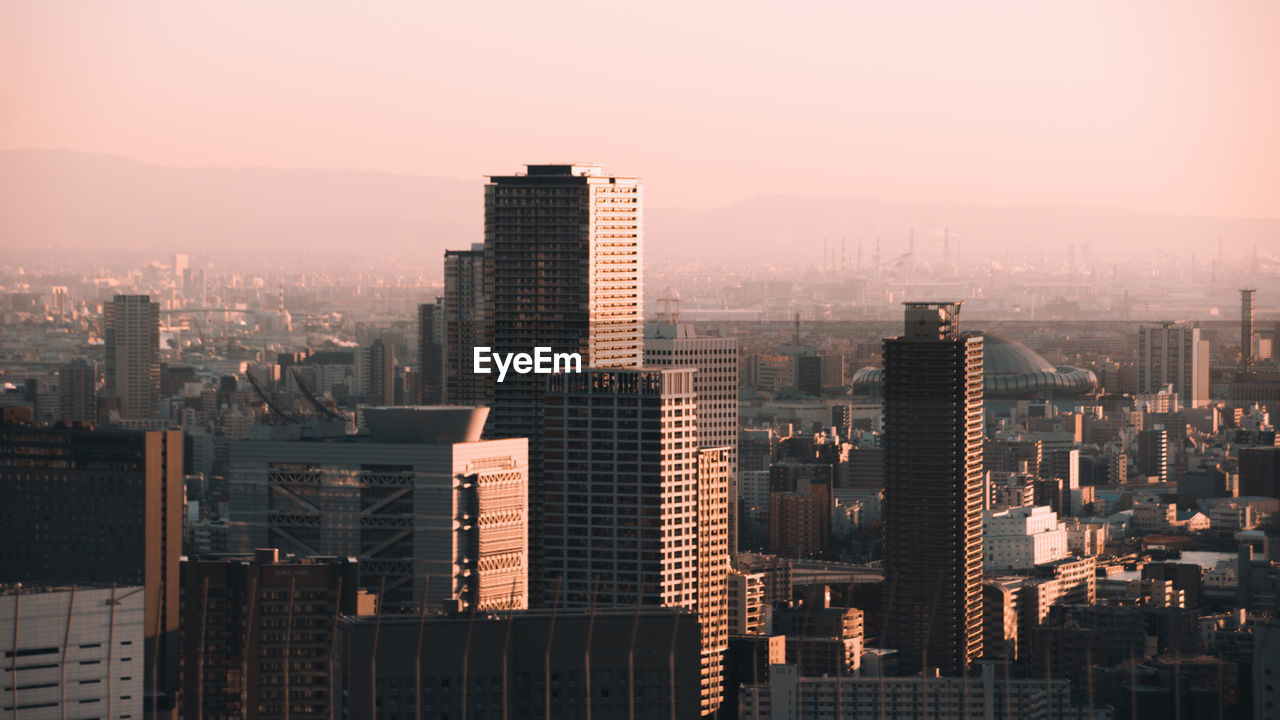 Modern buildings in city against sky during sunset