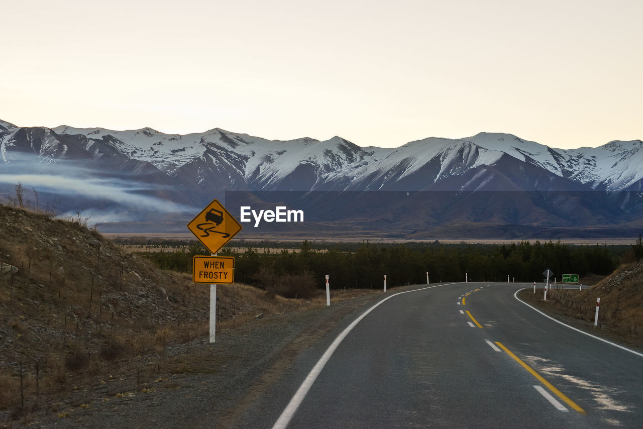 Road sign by mountains against sky