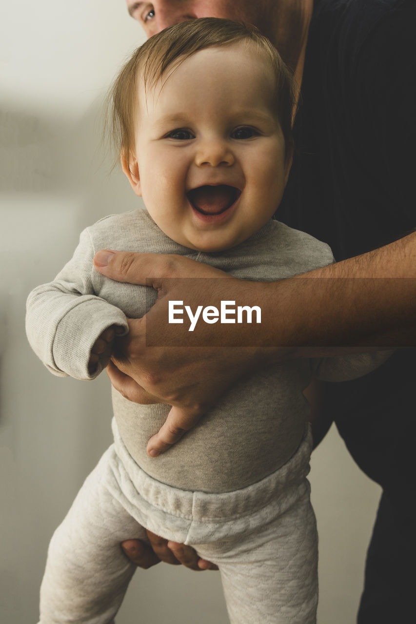 PORTRAIT OF CUTE BABY GIRL STANDING IN KITCHEN