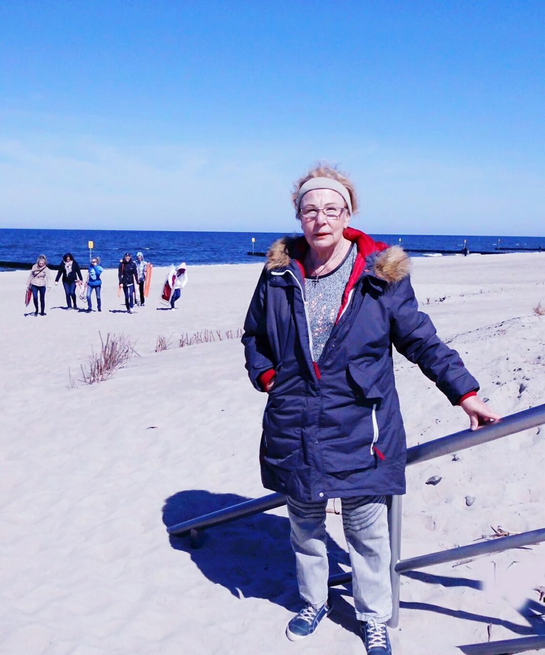 Portrait of woman standing at sandy beach against sky on sunny day