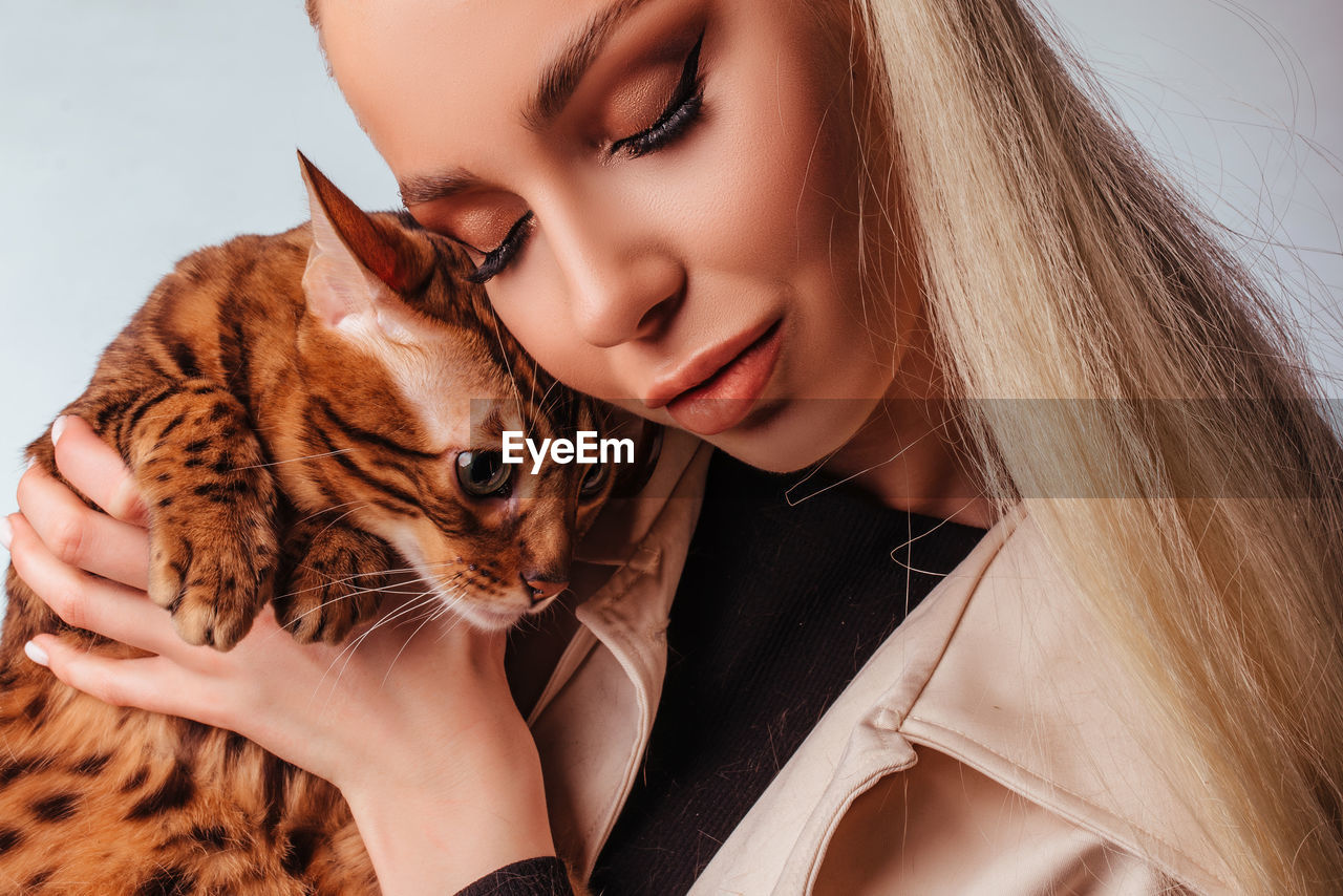 Portrait of an attractive cute young blonde woman with a bengal cat