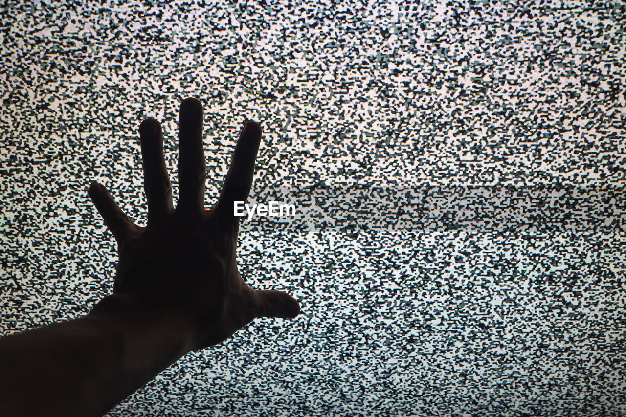 Close-up of person hand against television