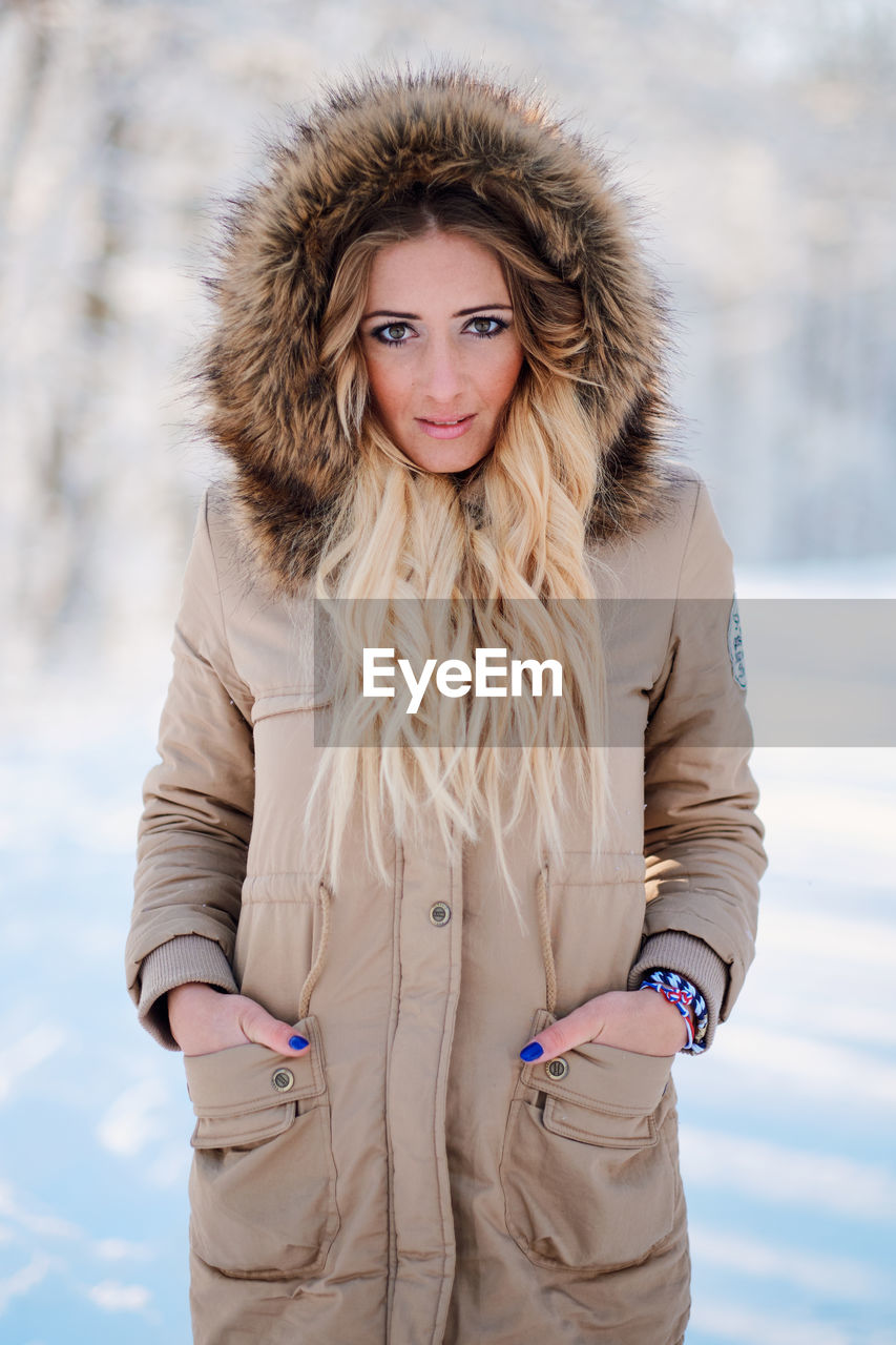 Portrait of young woman wearing warm clothing standing in forest