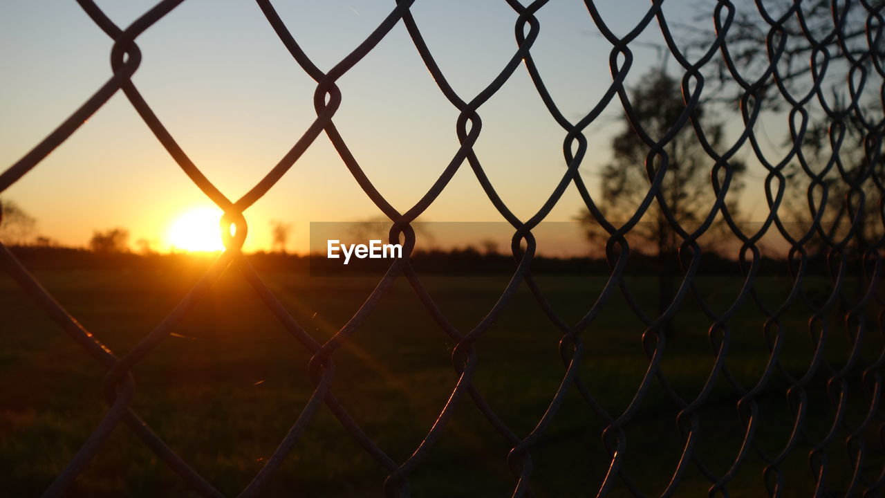 Close-up of chainlink fence during sunset