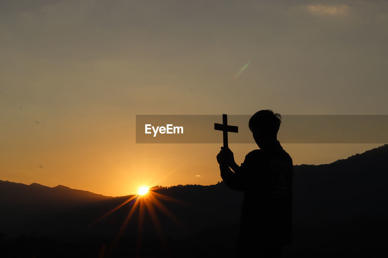 Silhouette man standing against orange sky