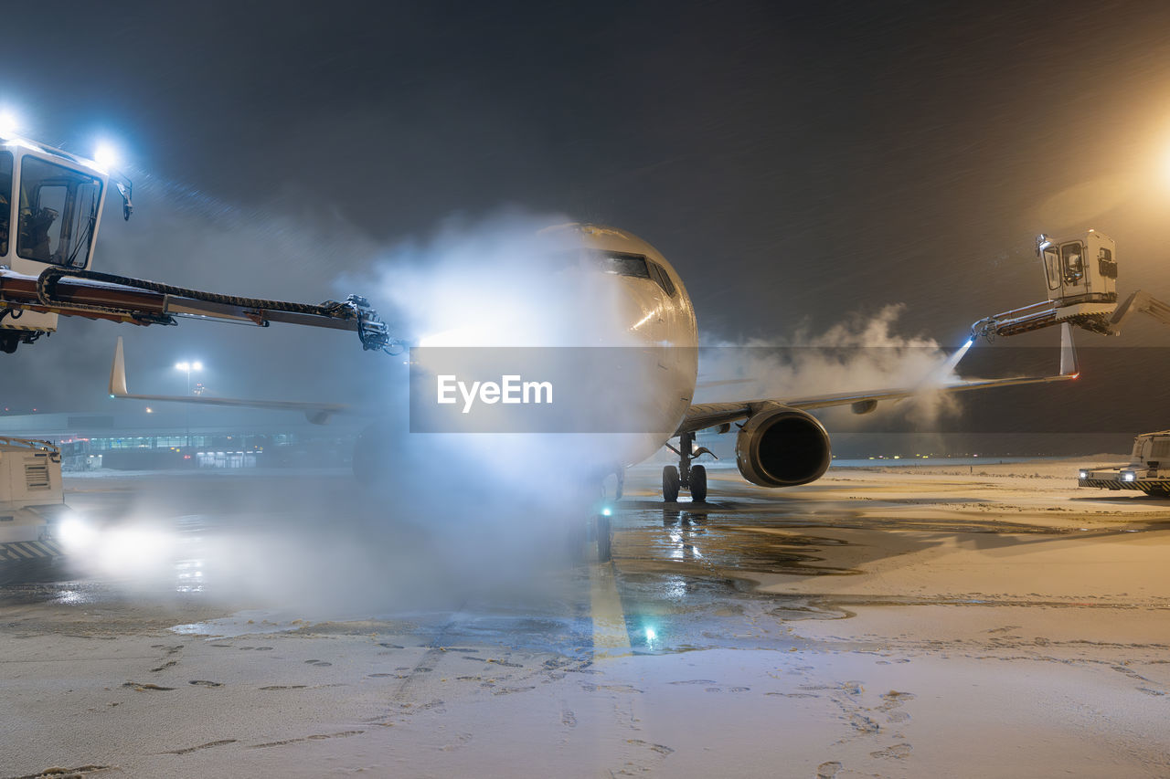 Deicing of airplane before flight. winter frosty night and ground service at airport.