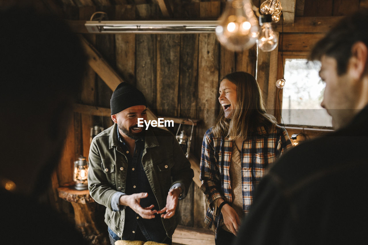 Cheerful woman talking with male friends during social gathering