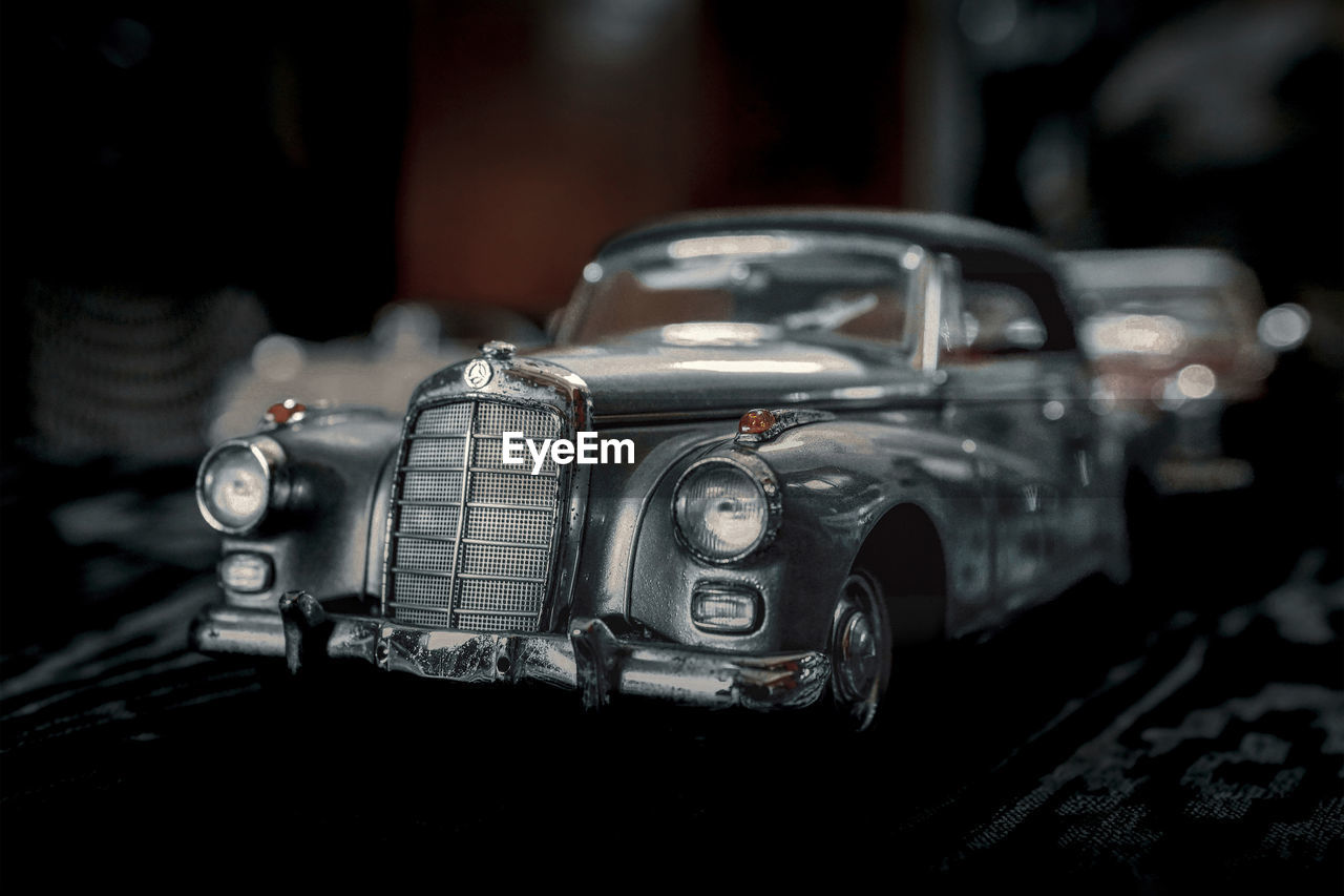 car, vehicle, mode of transportation, motor vehicle, land vehicle, retro styled, transportation, luxury vehicle, automobile, vintage car, indoors, close-up, focus on foreground, no people, headlight, metal, nostalgia, the past, history