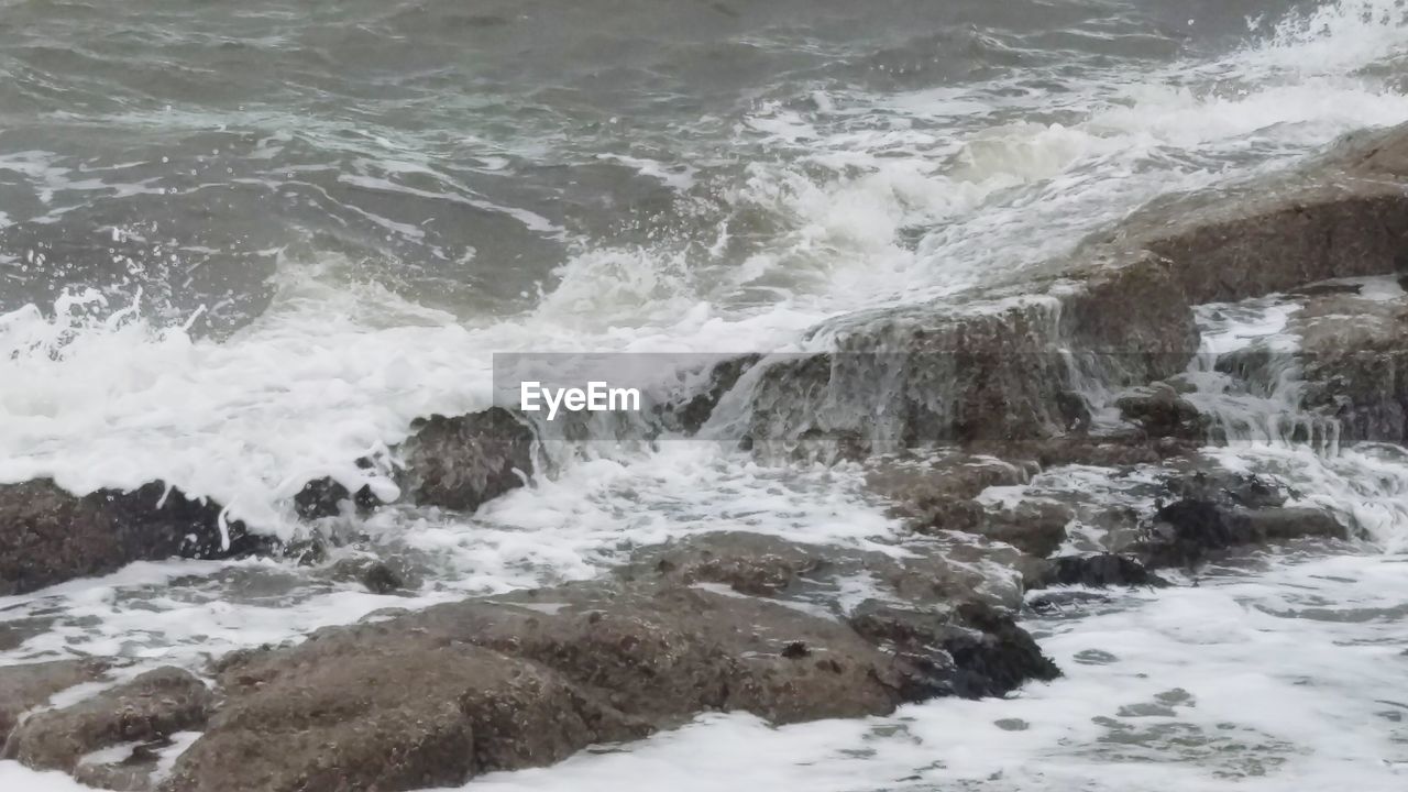 HIGH ANGLE VIEW OF WAVES BREAKING AT SEA