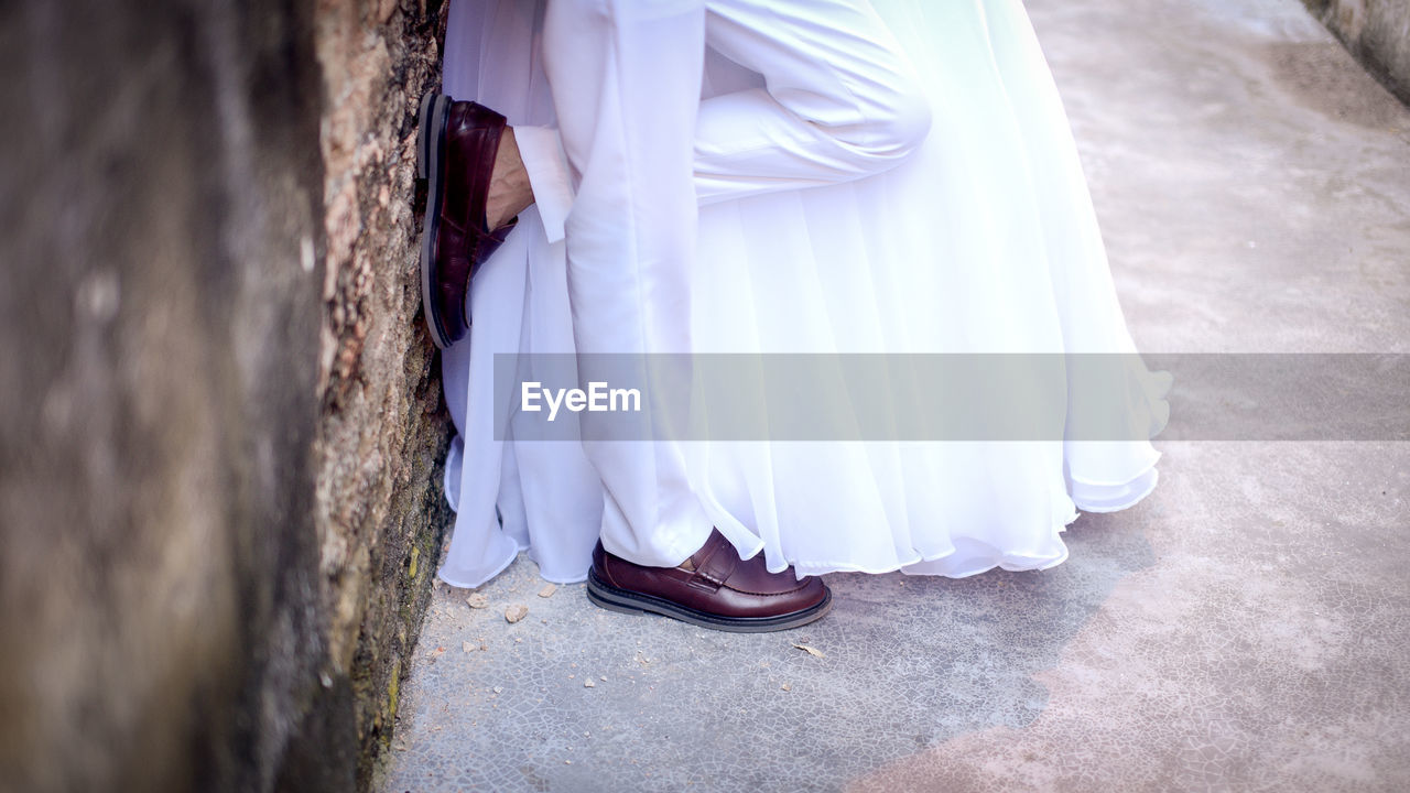 Low section of couple standing against wall